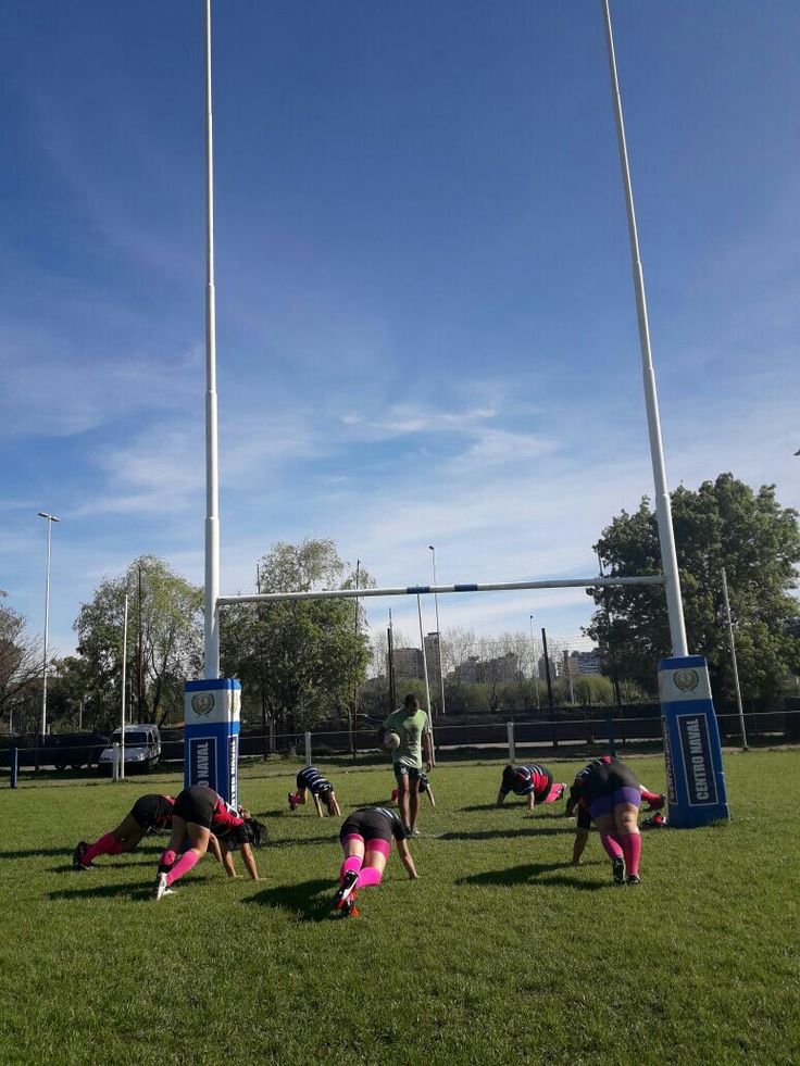 some people are doing exercises on the grass in front of two tall poles and flags