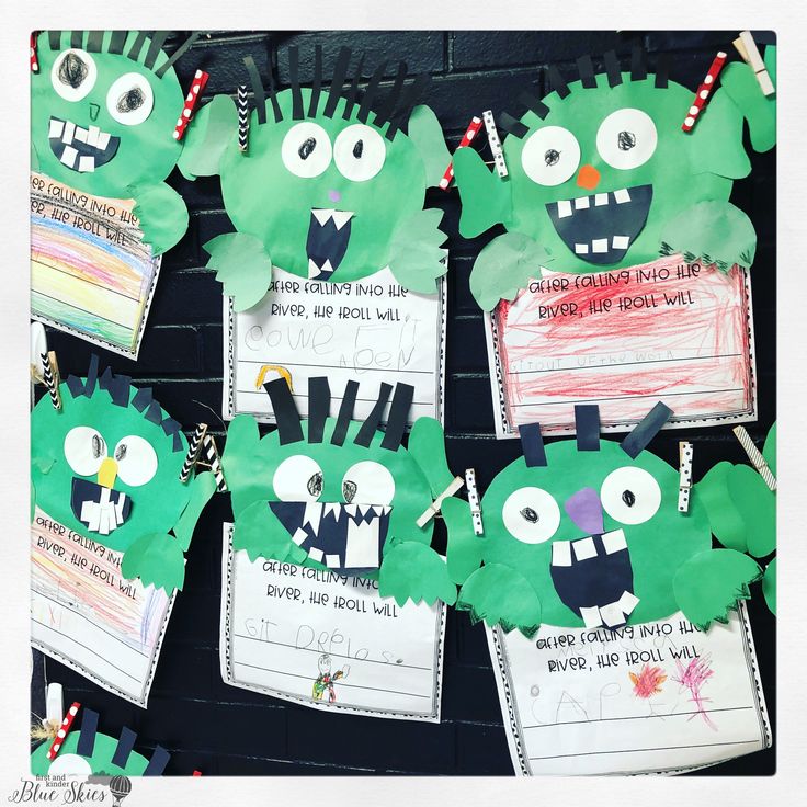 some green paper monsters are hanging on a black wall with other items attached to them