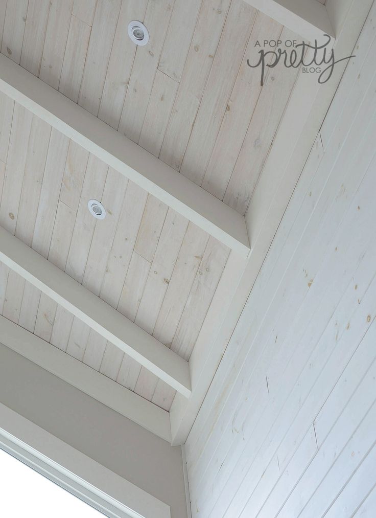 an empty room with white painted walls and wood paneling on the ceiling is shown