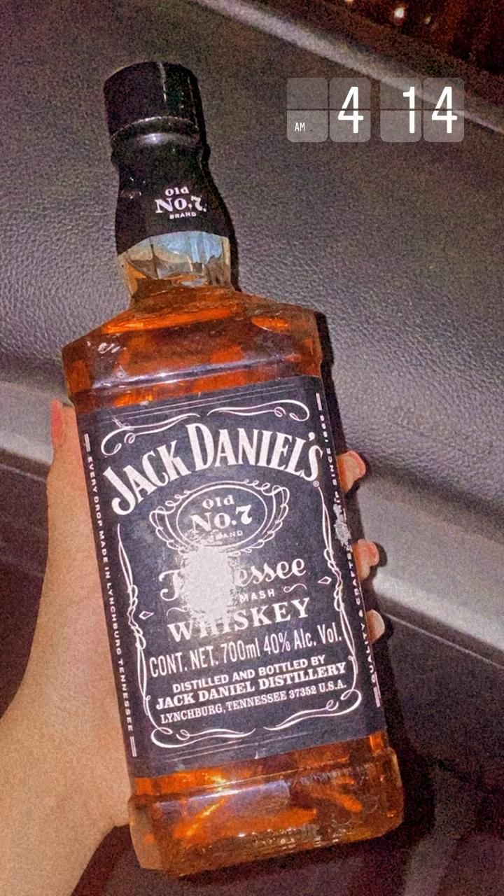 someone holding up a bottle of jack daniels whiskey