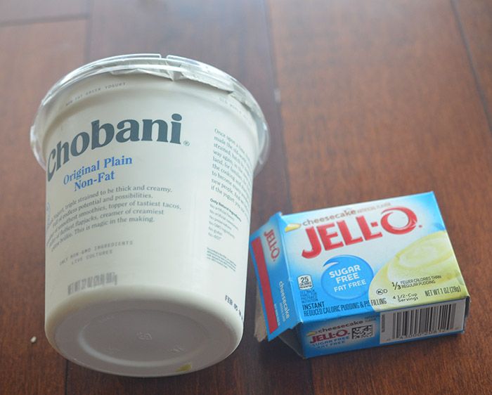 a yogurt cup next to a carton of jello on a wooden table