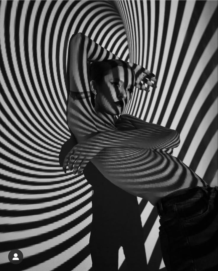 a man standing in front of a black and white striped wall with his arms spread out