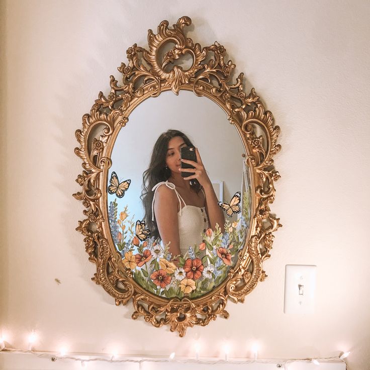 a woman taking a selfie in front of a mirror with fairy lights on the wall