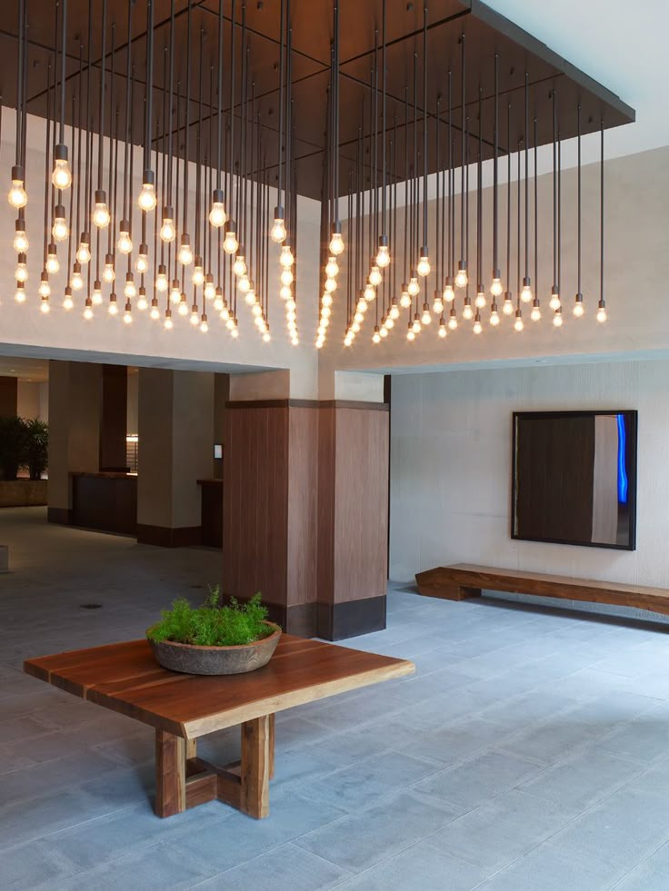 a large room with a wooden table and lights hanging from it's ceiling above