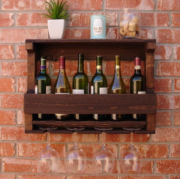 several wine bottles and glasses are on a shelf next to a brick wall with a potted plant