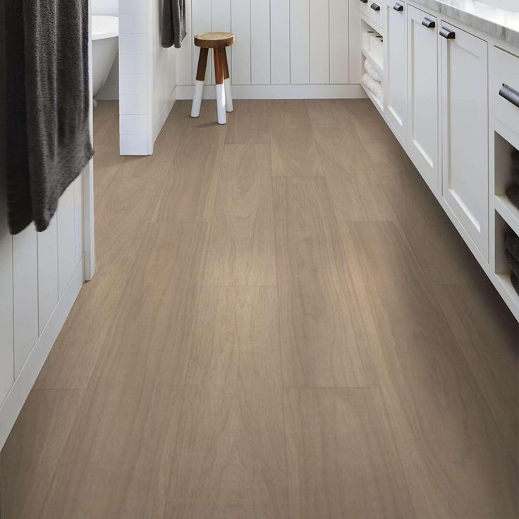 a bathroom with white cabinets and wood flooring