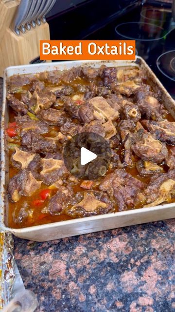 a baking pan filled with cooked oxtails on top of a counter next to an oven