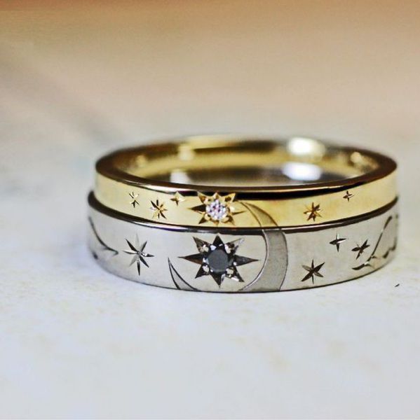 two wedding rings with stars and moon designs on the sides, sitting on a table