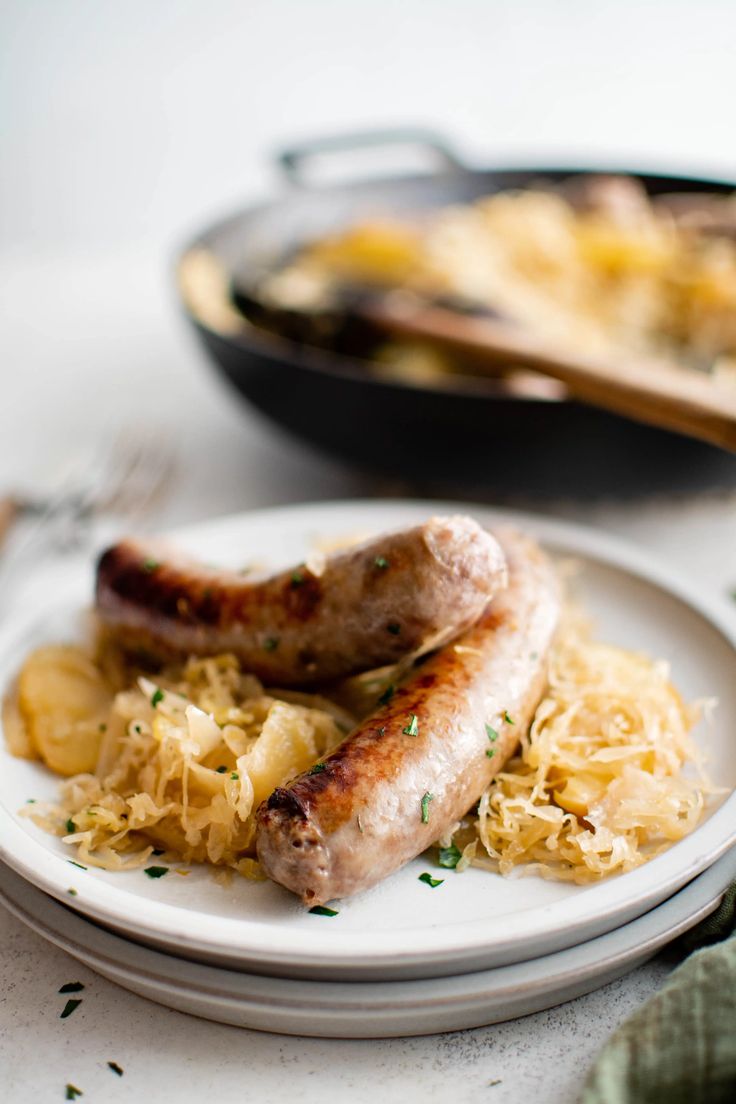 two sausages and sauerkraut on a plate with a skillet in the background