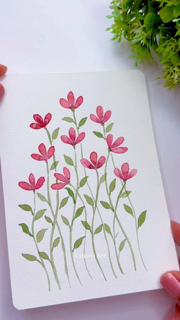 a hand holding a card with watercolor flowers on it