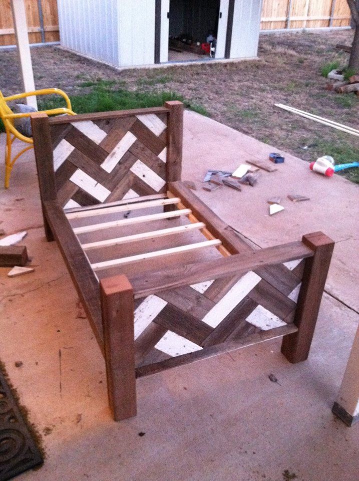 a wooden bed frame sitting on top of a cement floor next to a yellow chair