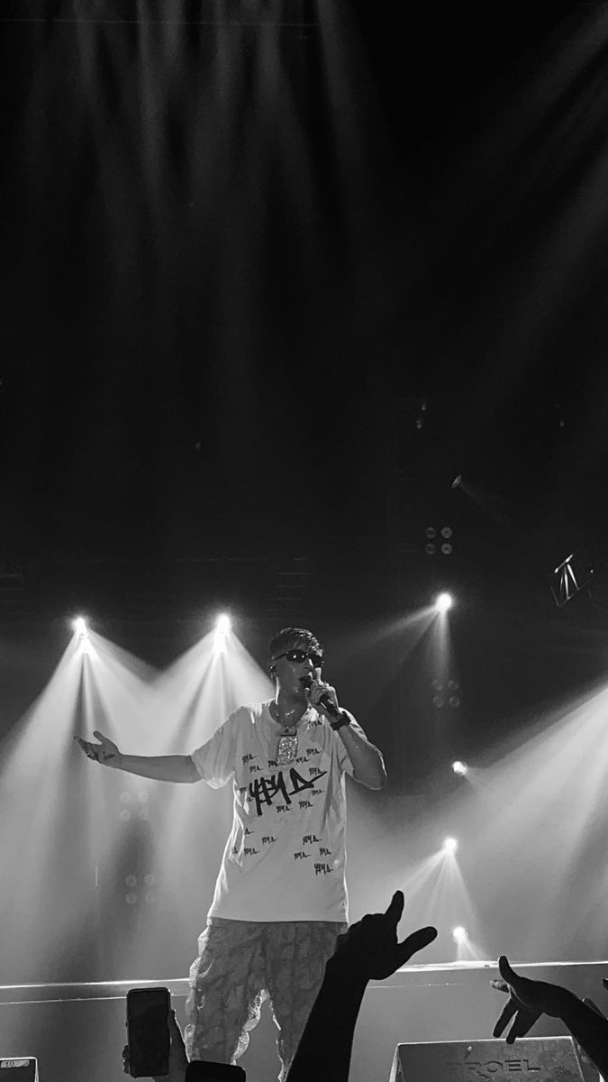 a man standing on top of a stage with his arms out in front of him