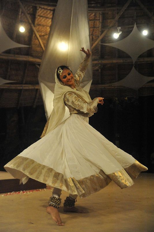 a woman in a white and gold dress dancing