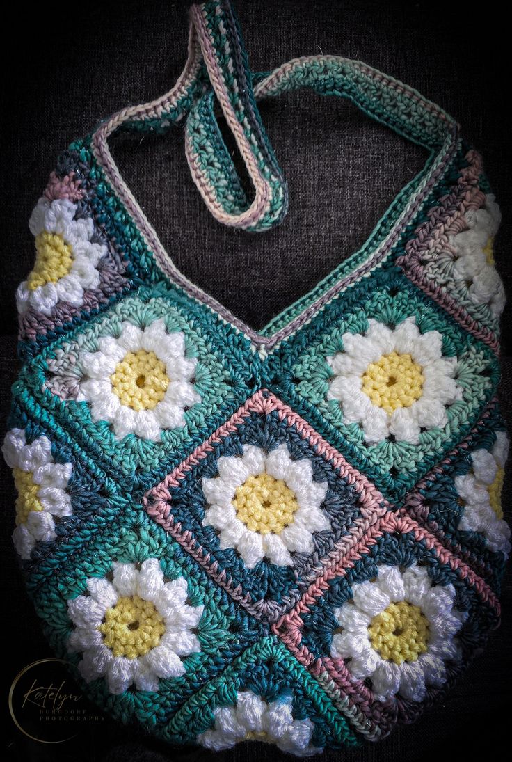 a crocheted granny bag with flowers on the front and sides, sitting on a black background