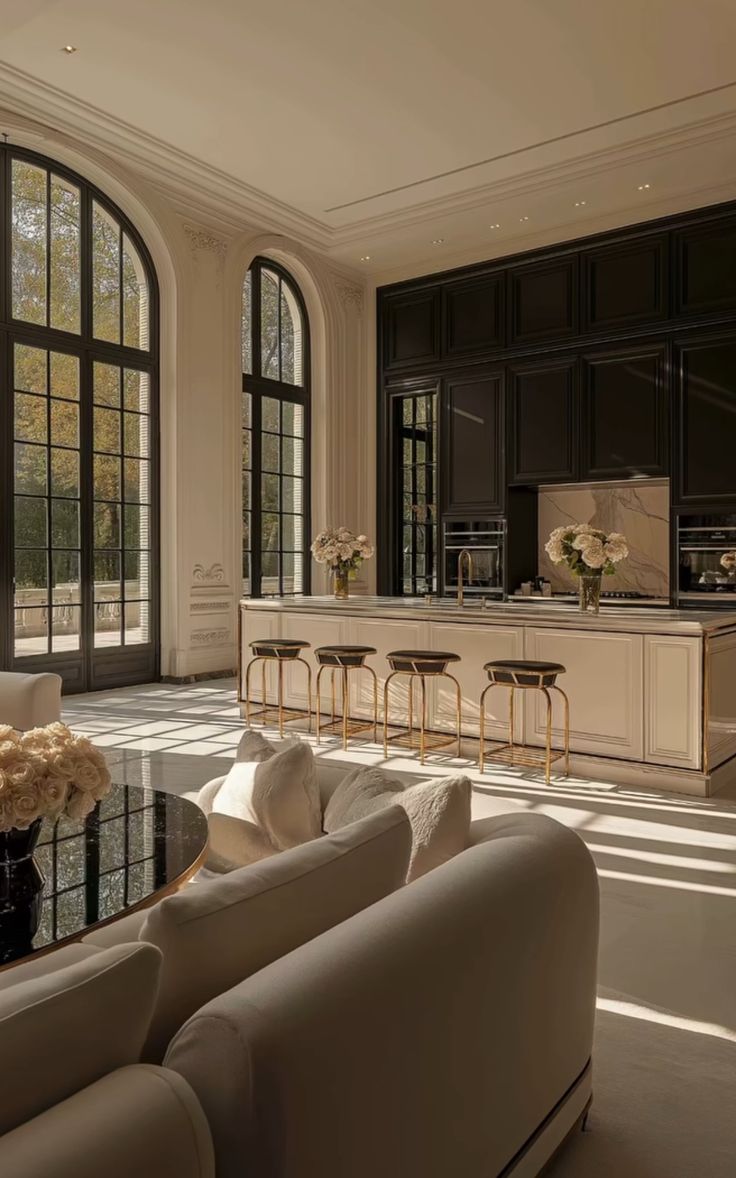 a living room filled with white furniture and large windows next to a kitchen counter top