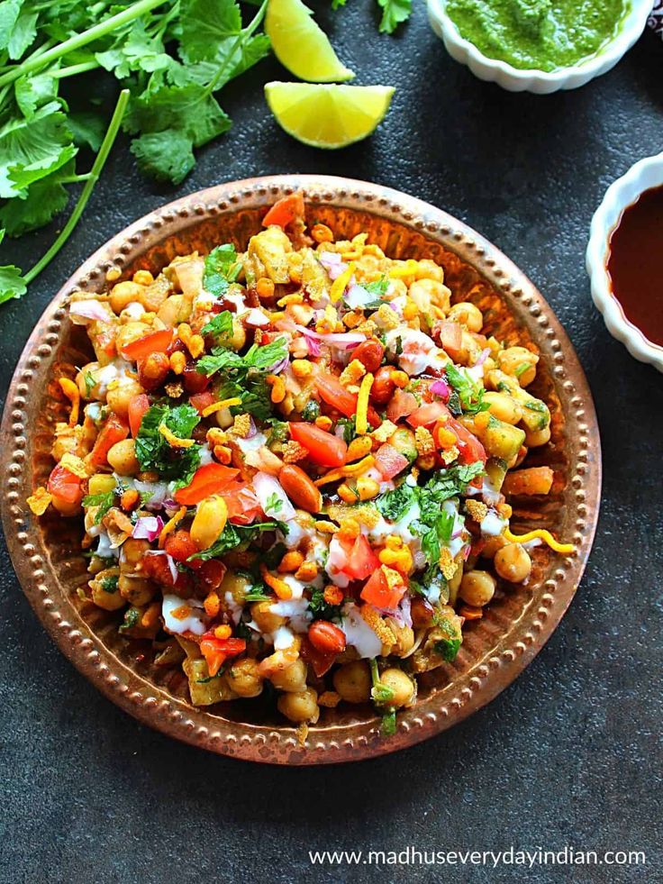 a bowl filled with corn and vegetables next to cilantro, lime wedges and ketchup