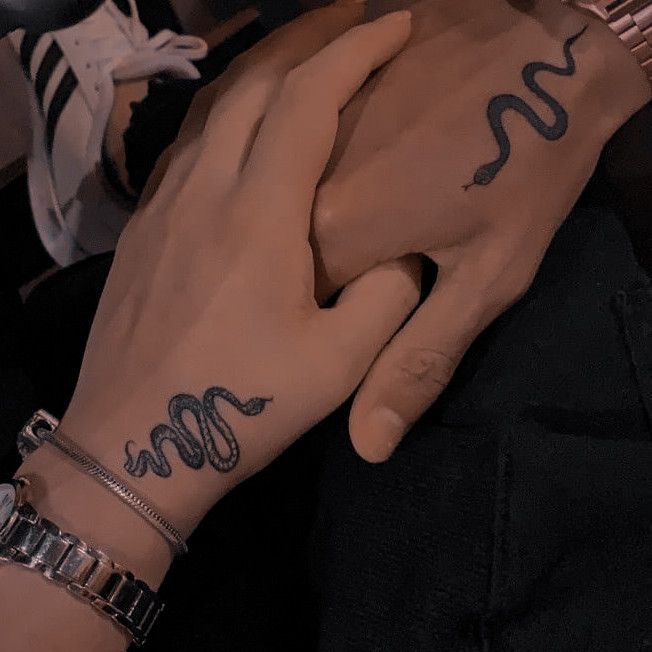 two hands holding each other with tattoos on them