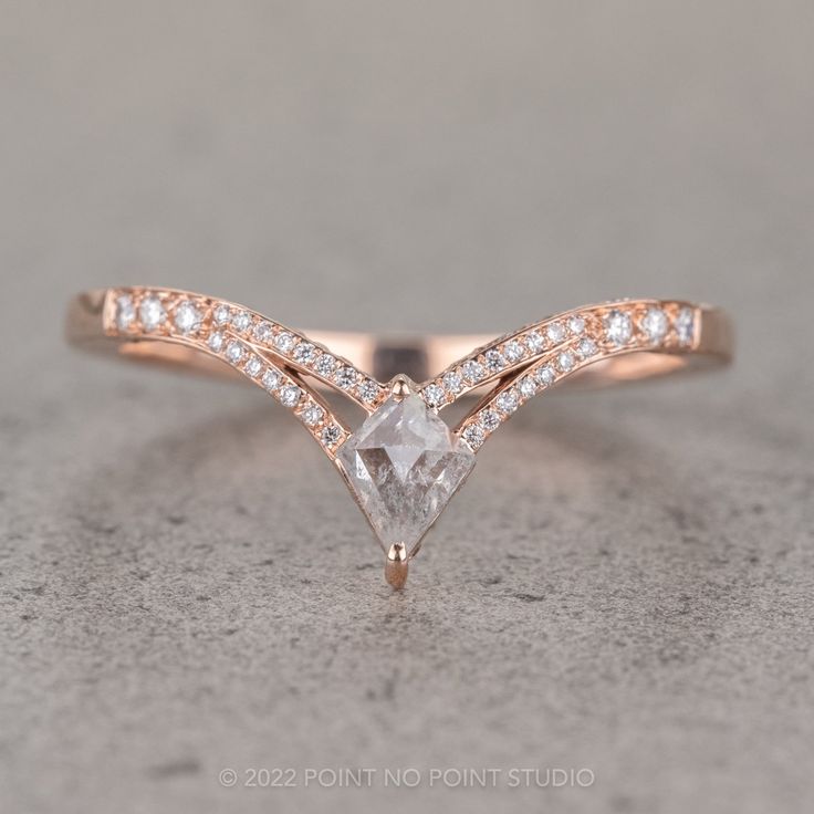 a rose gold engagement ring with a pear shaped diamond and pave diamonds on the band