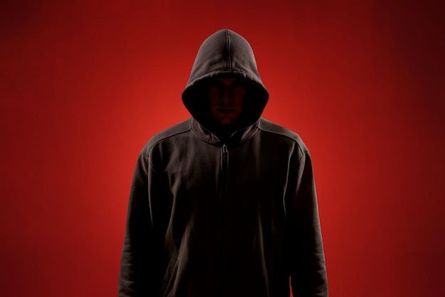 a man in a hoodie standing against a red background