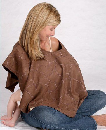 a woman sitting on the ground wearing a brown ponchy top and blue jeans