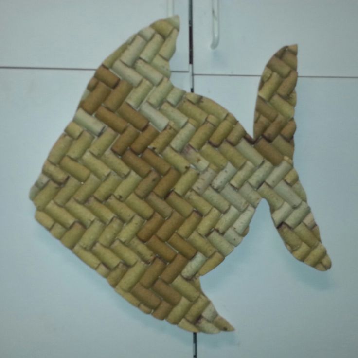 a fish made out of woven material sitting on top of a tile floor next to a wall