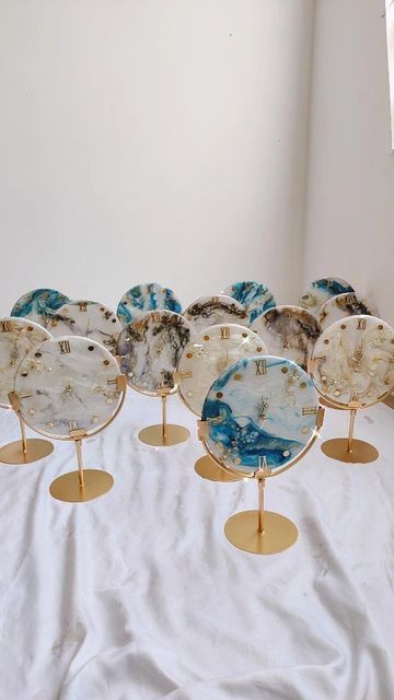 seven decorative glass plates on gold stands in front of a white wall and flooring