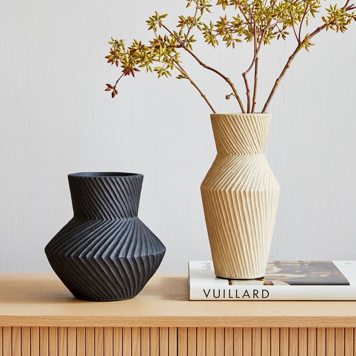 two vases sitting on top of a table next to each other with flowers in them