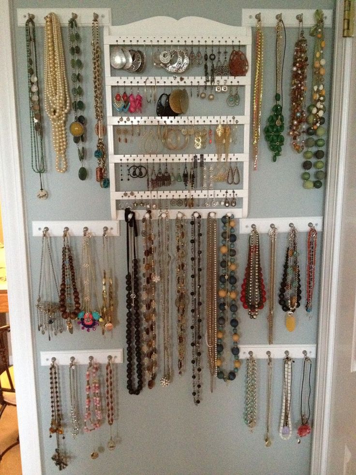 a closet filled with lots of necklaces and bracelets hanging on the wall next to a door