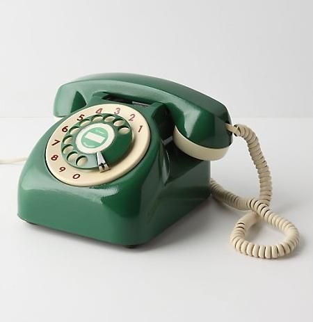 an old - fashioned green phone is sitting on the table with its cord still attached