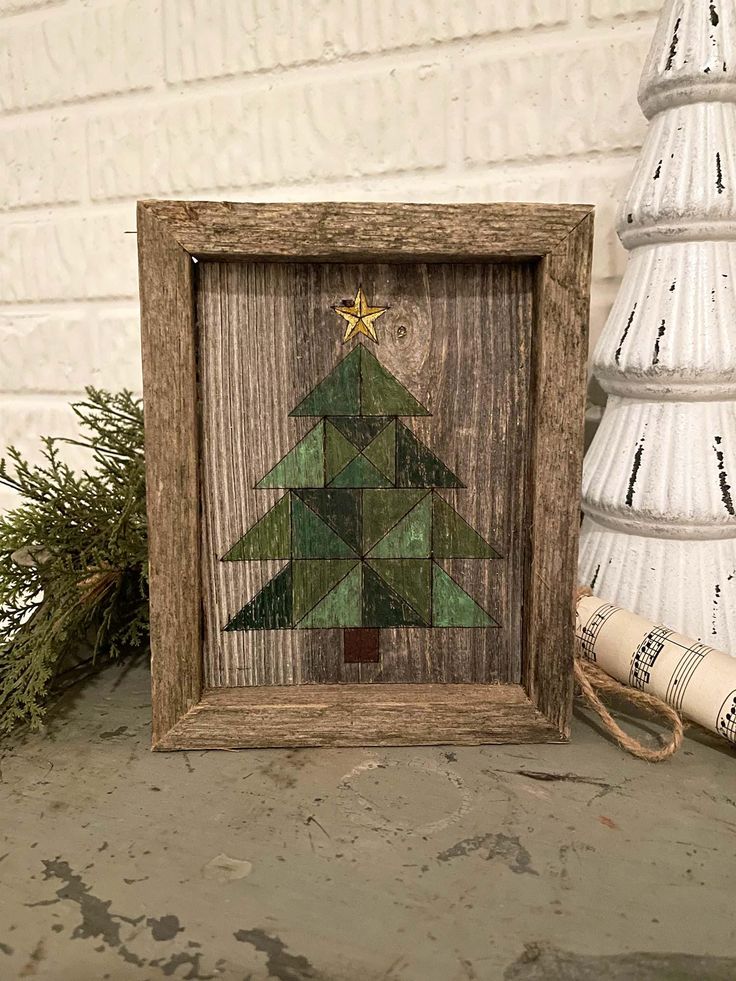 a wooden frame with a christmas tree on it next to a small white pine tree