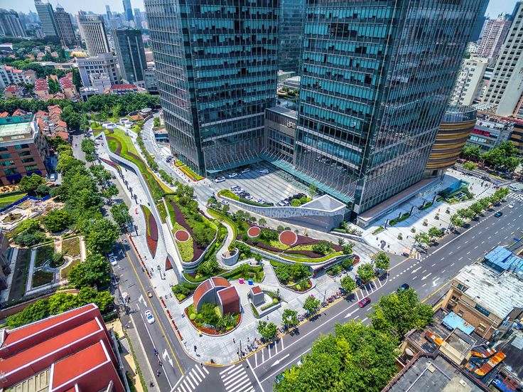 an aerial view of a city with tall buildings and green spaces in the middle of it