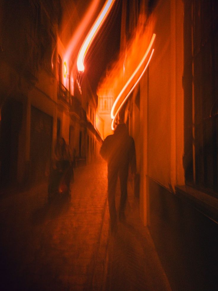 a man walking down a street at night with long exposure on his face and back