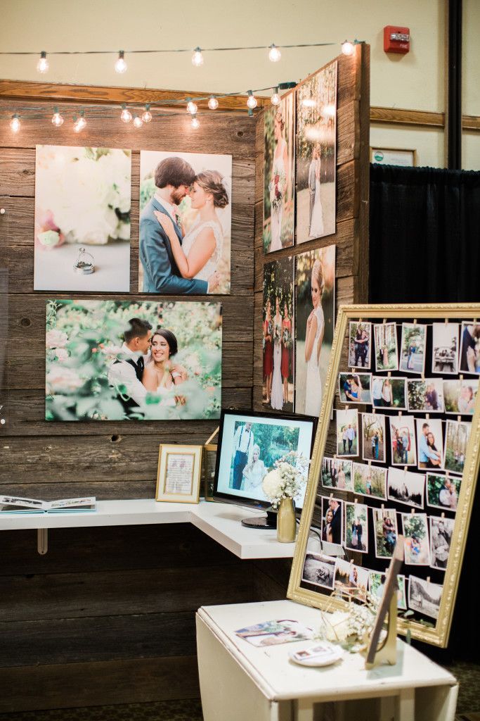 a table with pictures on it in front of a wooden wall and lights strung from the ceiling