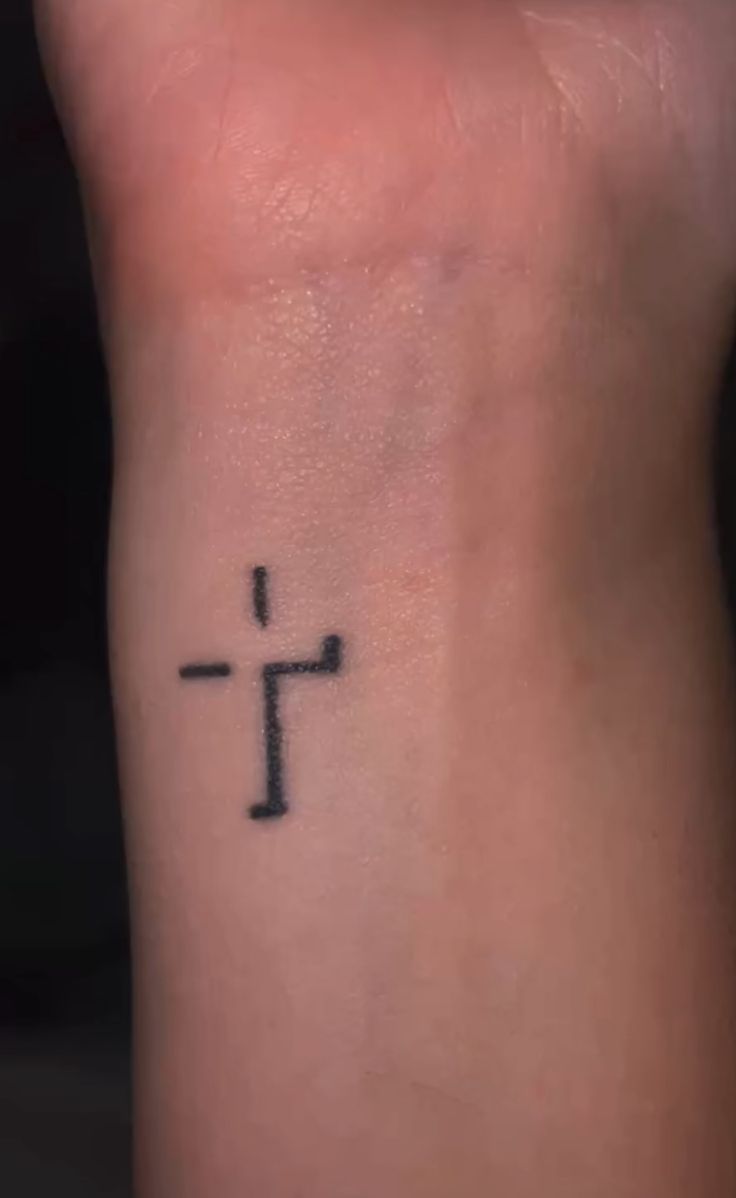 a small cross tattoo on the wrist