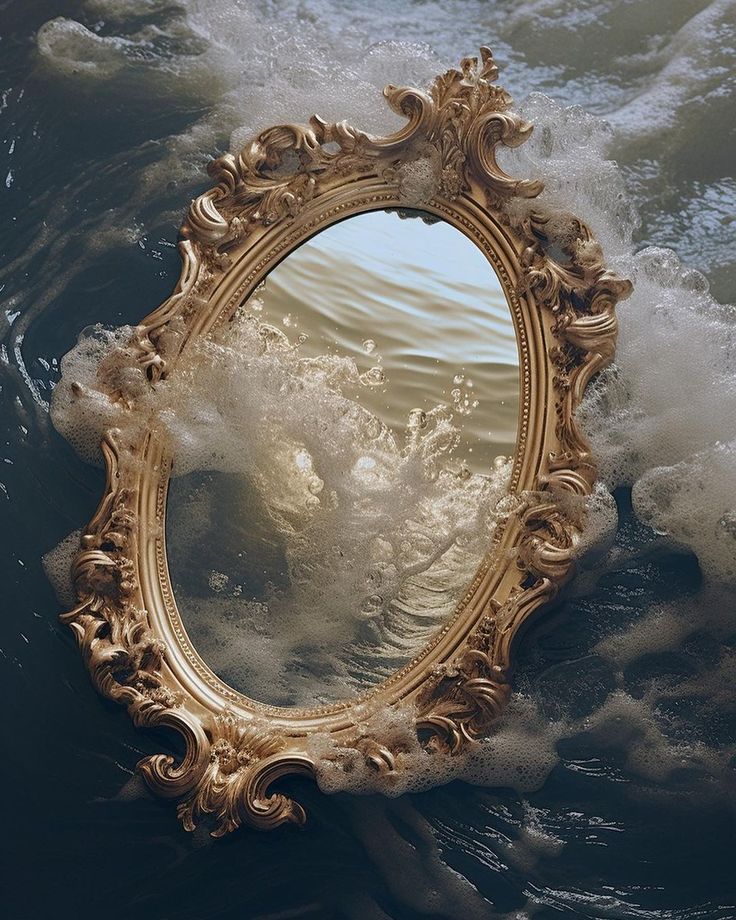 an ornate gold framed mirror floating on top of the ocean waves in front of it