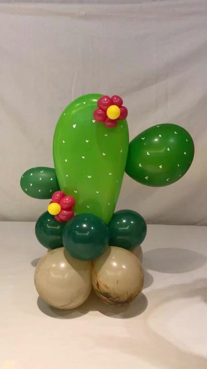 a green cactus with red flowers on it's head sitting on top of two balls