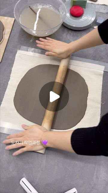 two hands are rolling out dough onto a table