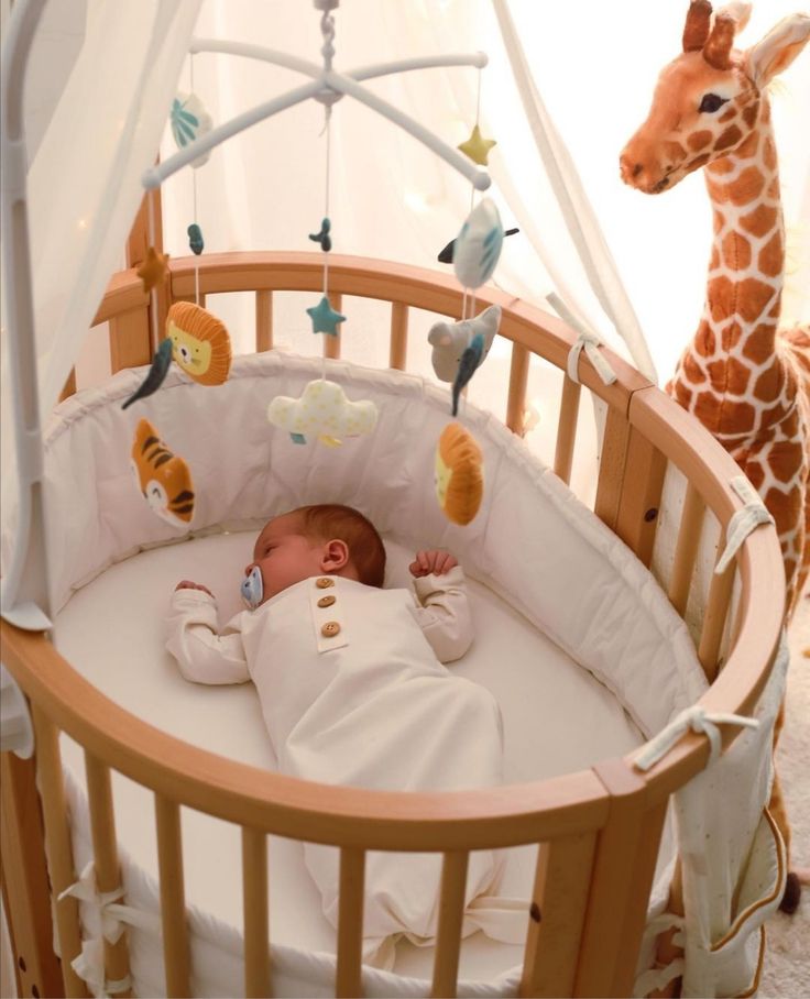 a baby laying in a crib next to a giraffe