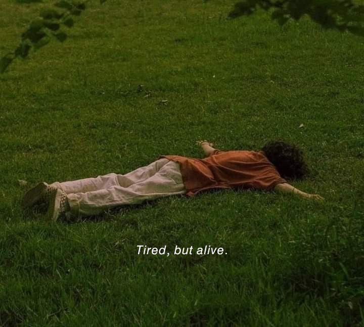 a person laying in the grass with an orange shirt on