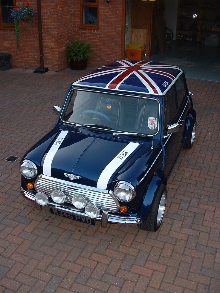 an old car with a british flag painted on it's hood is parked in front of a brick building