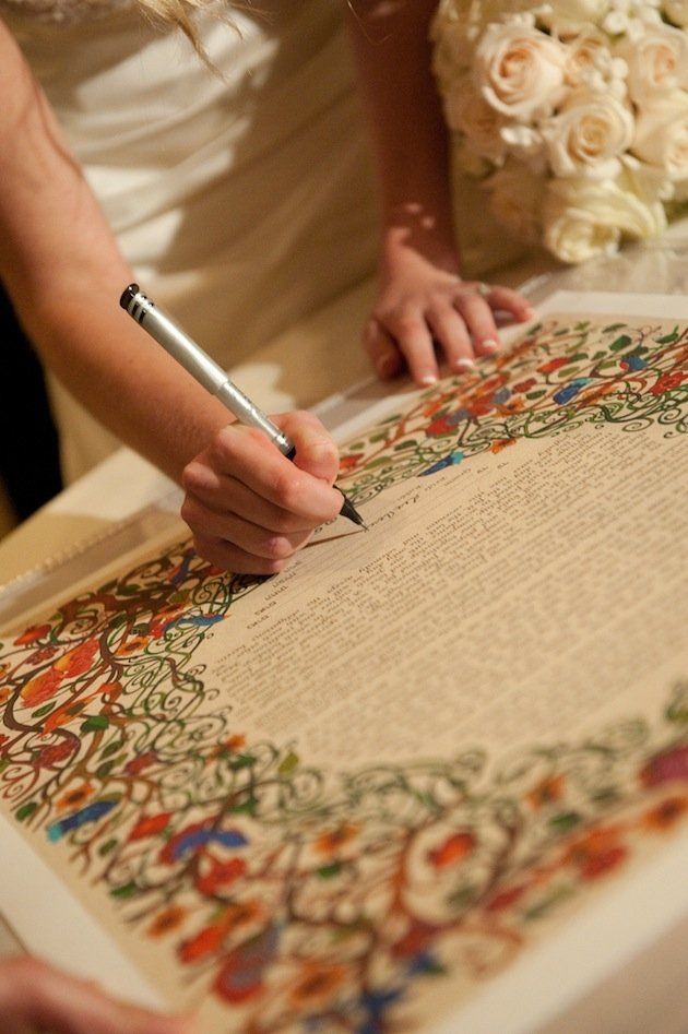 a bride and groom are signing their wedding vows in an old book with flowers on it