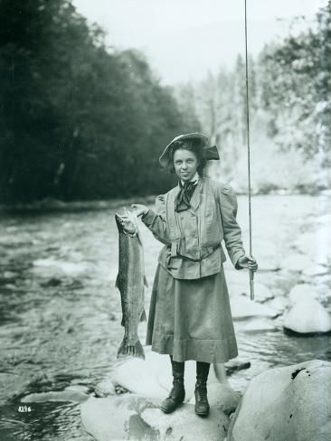 an old photo of a woman holding a fish in her hands and standing on the edge of a river