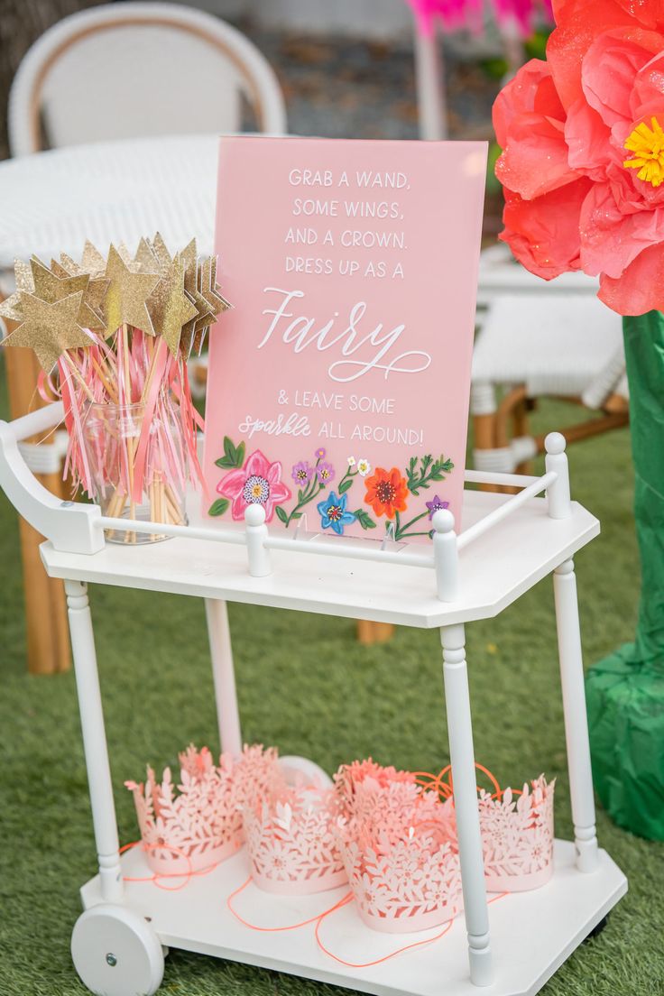 a sign that is sitting on top of a cart with some flowers and candles in front of it