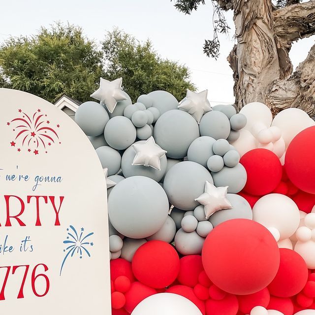 balloons and stars are on display in front of a party sign