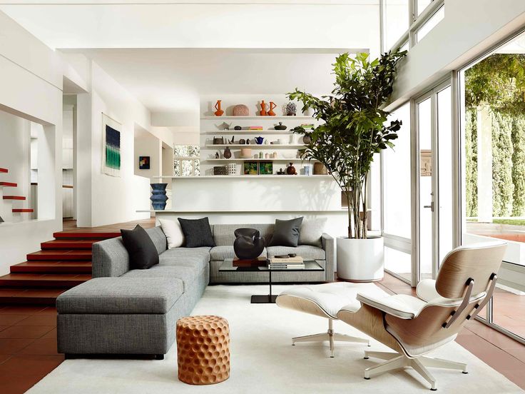 a living room filled with furniture and lots of windows next to a stair case that leads up to the second floor