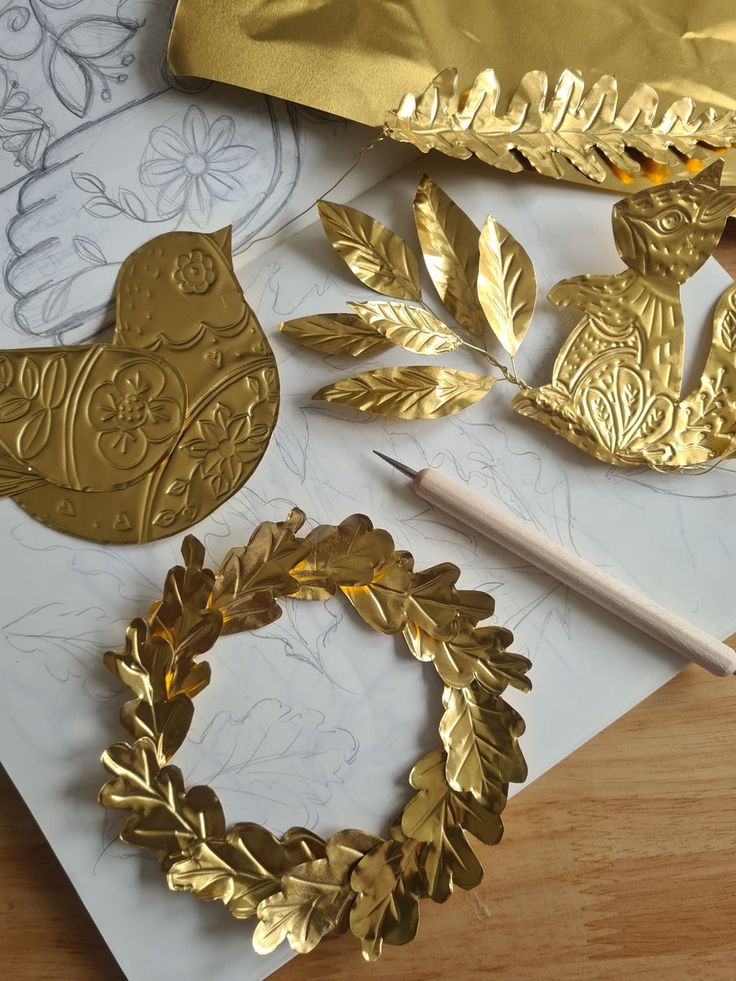 some gold decorations are laying out on a table with a pencil and ruler next to them