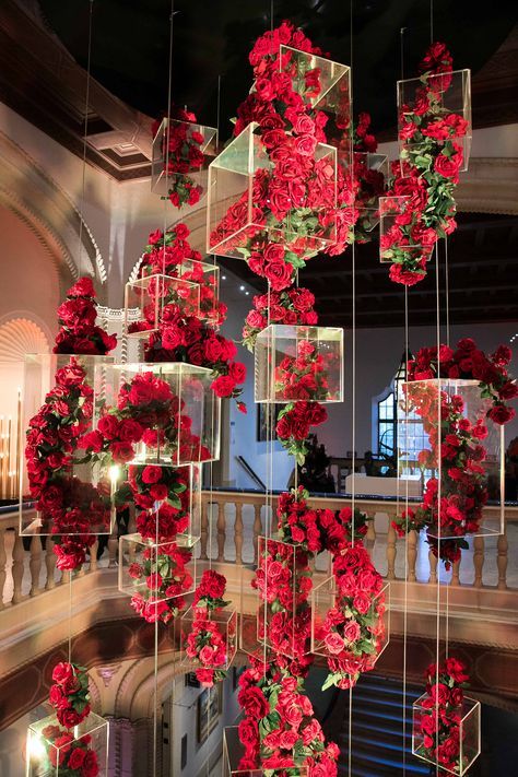 red flowers hanging from the ceiling in a room with chandelier and staircases