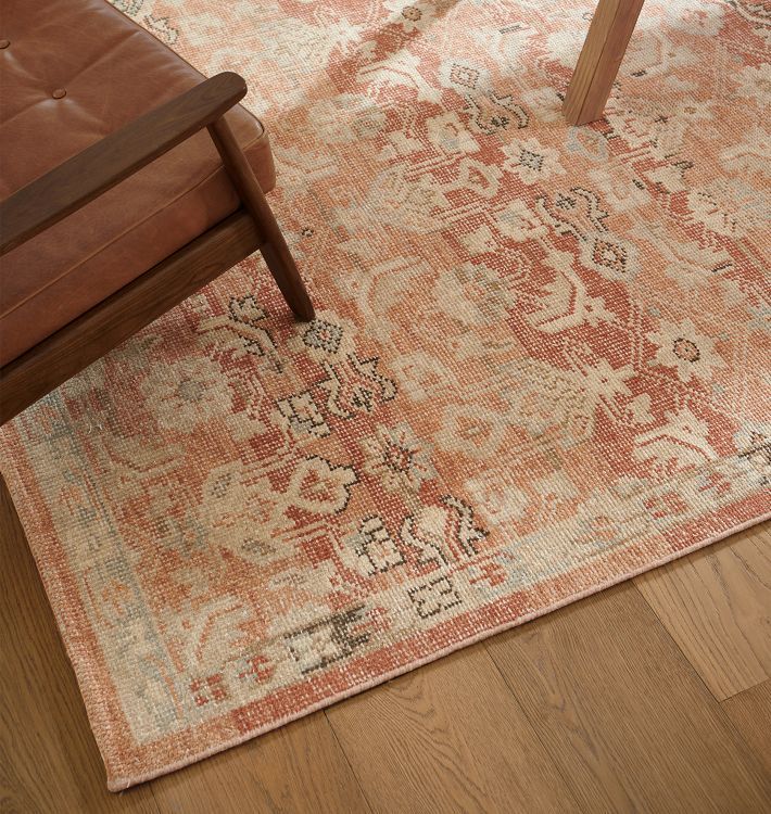 an orange and beige area rug with a wooden chair in the corner next to it