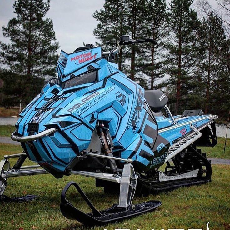 a blue and black snowmobile parked on the grass