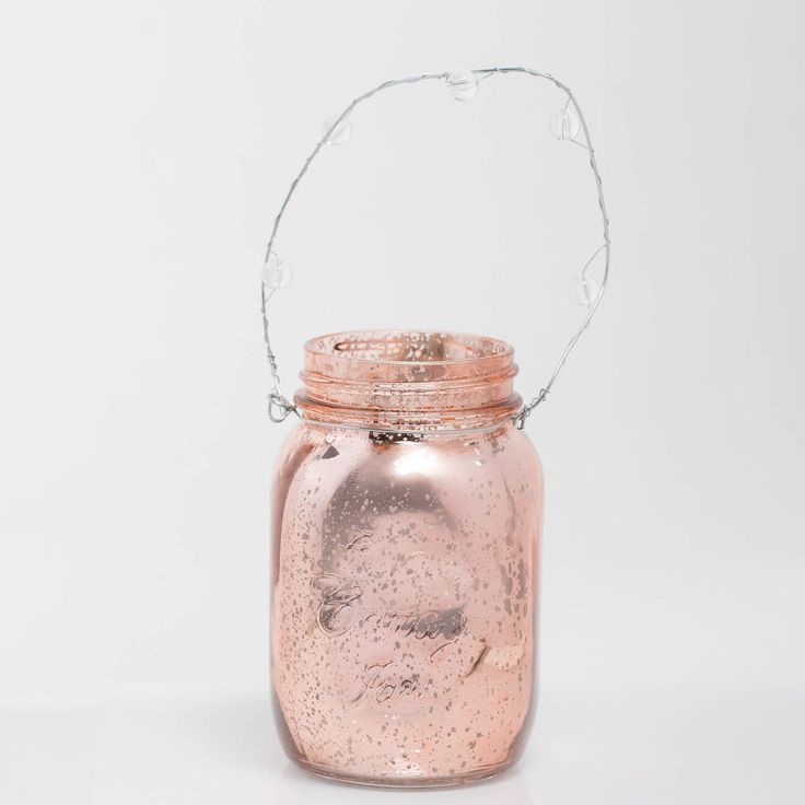 a pink glass jar with water pouring out of it and a handle on the top